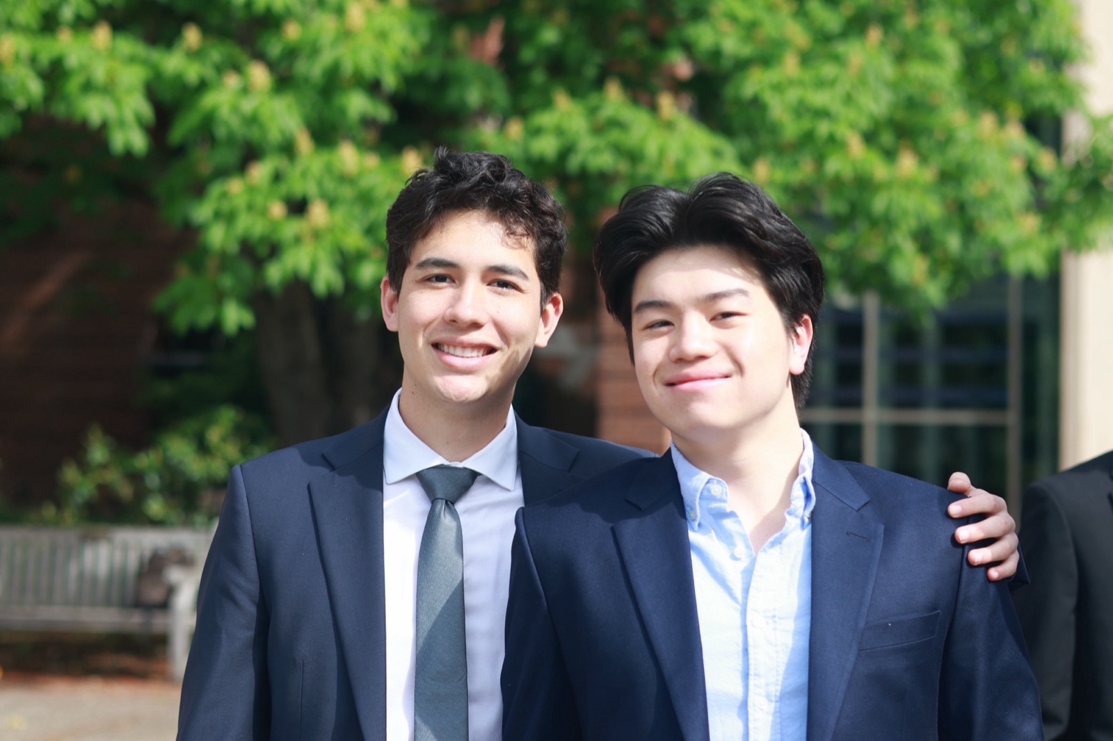 Two OQG members in suits, smiling outdoors