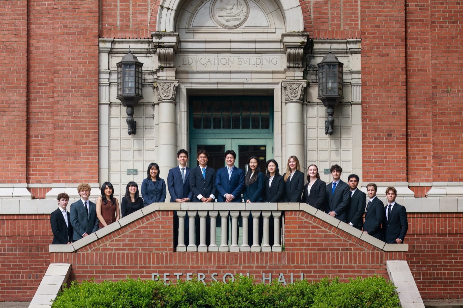 The full Oregon Quant Group team in suits on the steps of Peterson Hall