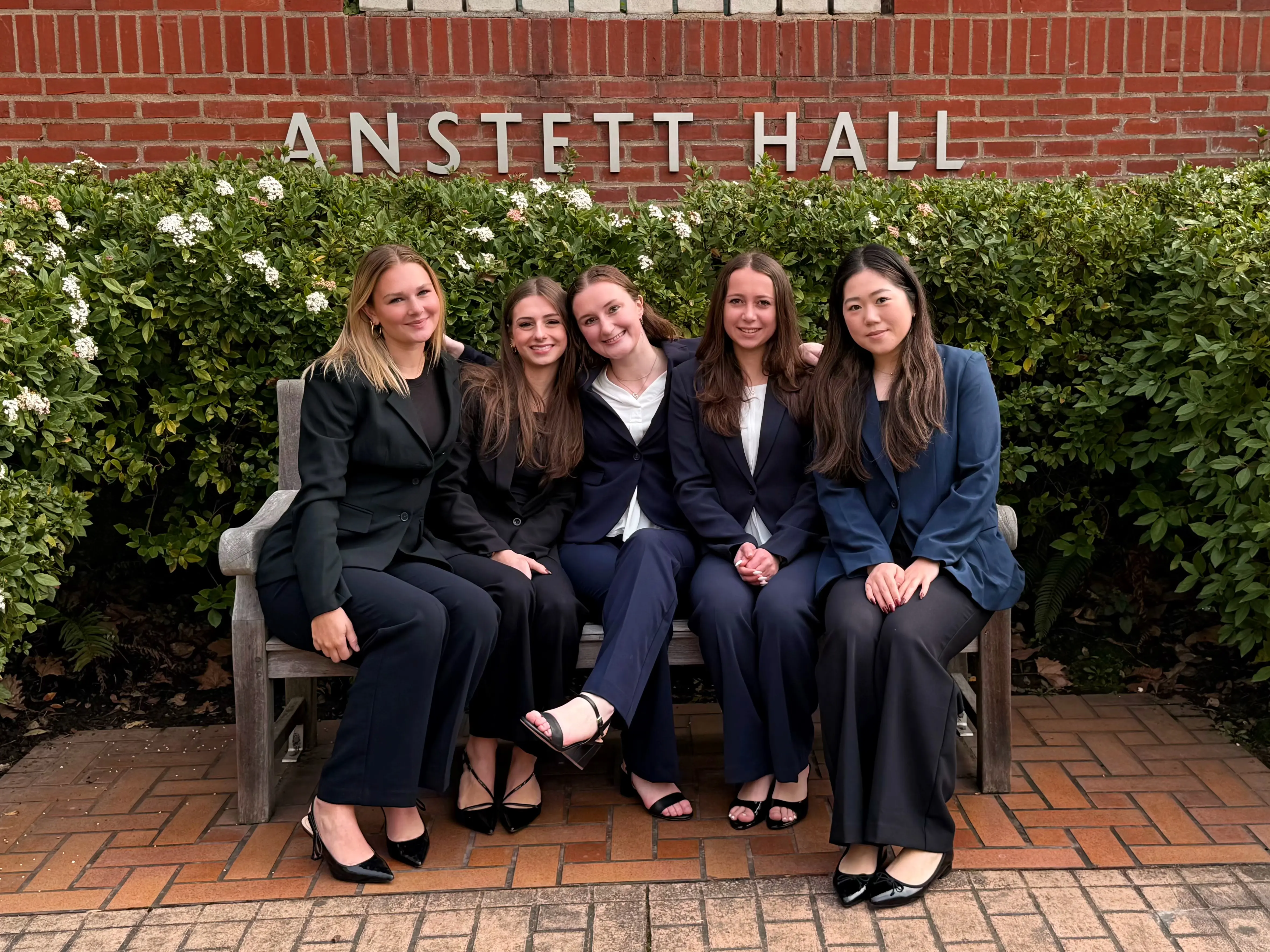 Five members in suits on a bench outside Anstett Hall